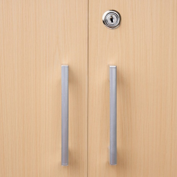 Vue rapprochée poignées métalliques et serrure armoire basse en bois